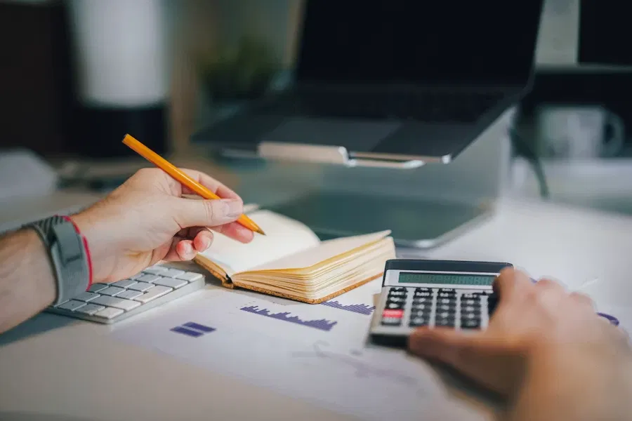 Working out a price by hand with a calculator and a notebook